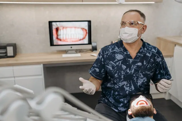 A dentist wearing a mask and gloves checks a patient's teeth in a modern dental clinic. A Practice Owner's Guide to HIPAA-Compliant Dental Marketing in the United States