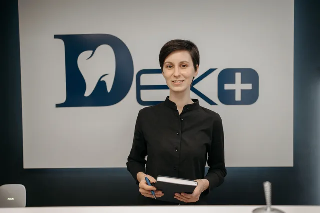 Smiling dentist holding a notebook in front of a clinic sign, promoting a welcoming and professional dental environment. How to manage dental reputation management: the short version