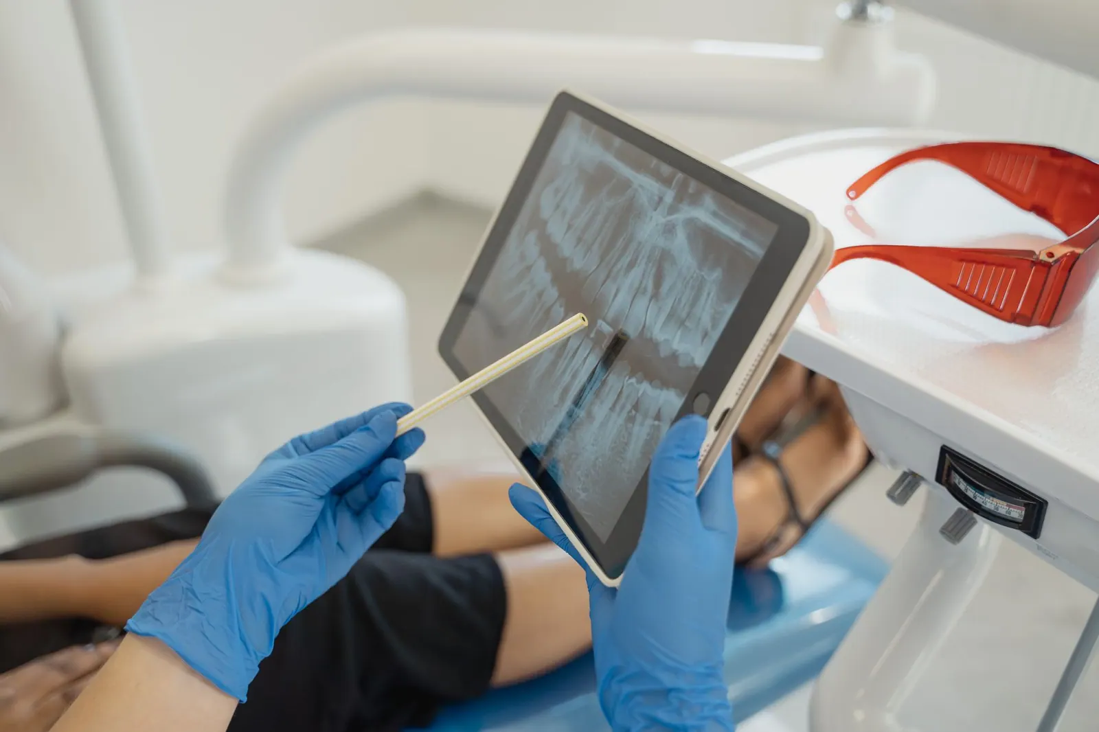 Dentist showing dental x-ray on tablet to patient in a modern clinic setting. Can You Remove a False Google Review for a Dental Practice?