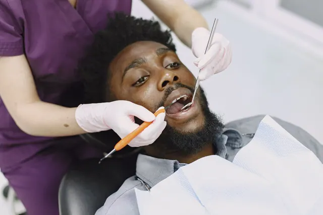 Dentist examining a man's teeth during a routine dental checkup. Zocdoc vs. Opencare: Which Dental Directory Sends Patients Who Show Up?