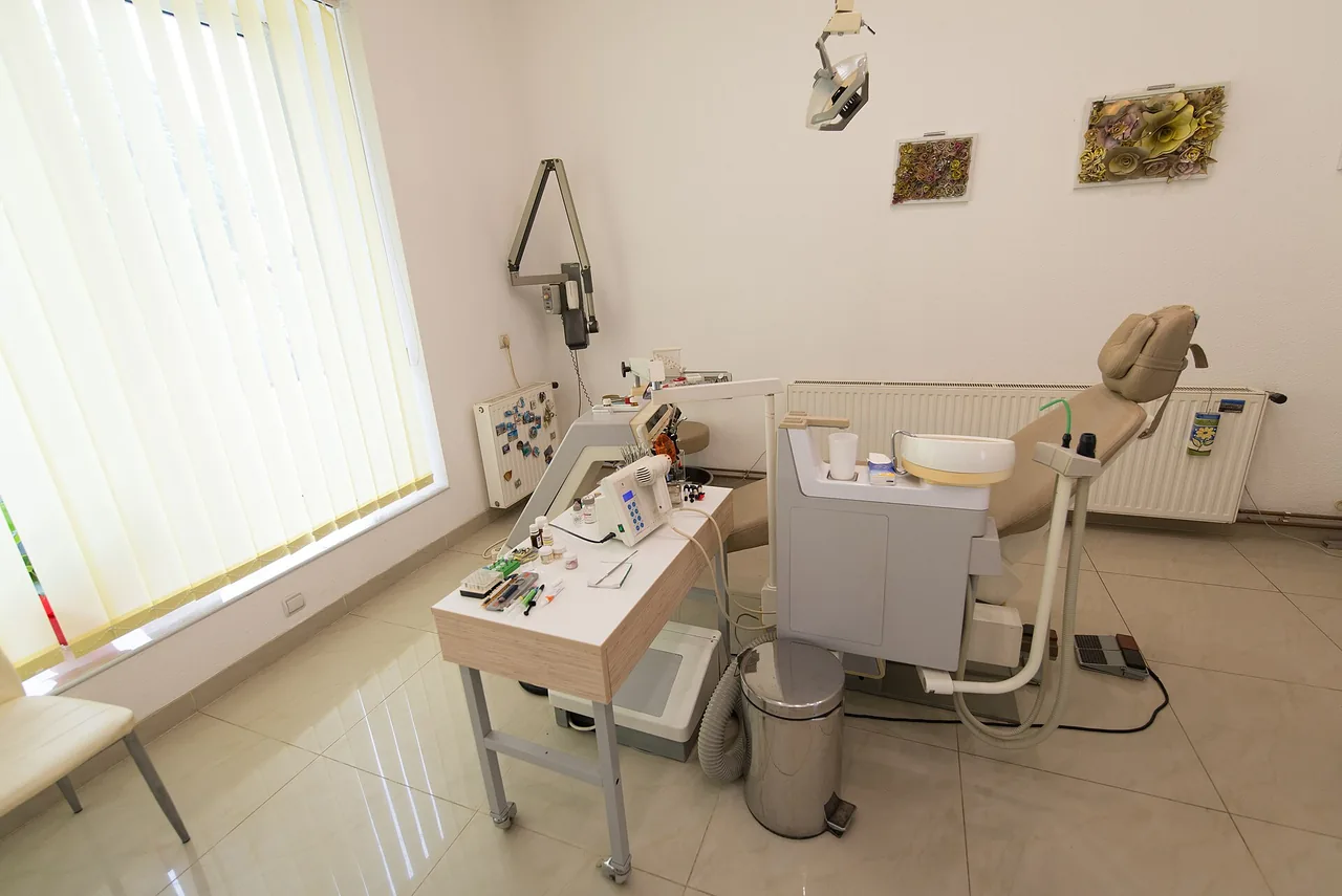 An empty dental treatment room with a chair and clinical equipment.